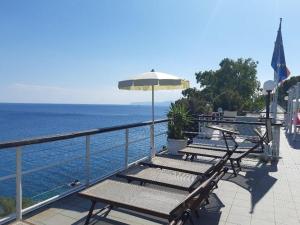 a row of benches with an umbrella and the ocean at Casa delle mimose in Varazze