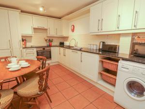 a kitchen with white cabinets and a table with chairs at May Cottage in Pentewan