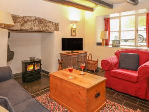 a living room with a red couch and a fire place at Churchgate Cottage in Bodmin