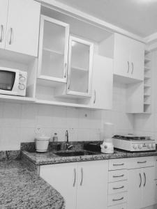 a kitchen with white cabinets and a sink and a microwave at Flats Residence Bueno in Goiânia