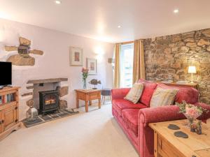 a living room with a red couch and a fireplace at Bwthyn Bach in Nefyn