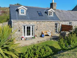 a stone house with a bench in front of it at Bwthyn Bach in Nefyn