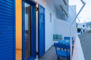 Habitación con puerta azul y balcón con 2 sillas. en Angeliki Seaside Hotel en Aliki