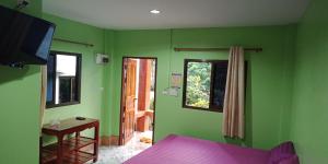 Schlafzimmer mit grünen Wänden, einem Bett und einem TV in der Unterkunft Yahle Villa เยห์เล่วิลล่า in Chao Lao Beach
