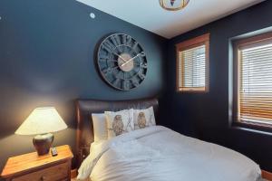 1 dormitorio con reloj en la pared y 1 cama en Tree Tops 15, en Big White