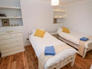 two twin beds in a room with wooden floors at Coeden Bach in Burry Port