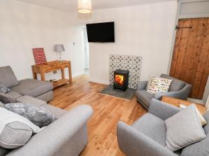 a living room with couches and a fire place at Coeden Bach in Burry Port