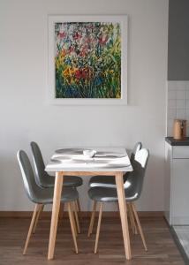 einen Esstisch und Stühle mit einem Gemälde an der Wand in der Unterkunft Apartment von Schivelbusch in Markkleeberg