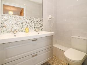 a white bathroom with a sink and a toilet at Holly Cottage in Criccieth