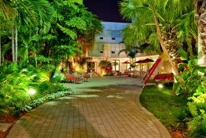 a walkway in a garden with palm trees and a building at Dorchester Hotel & Suites in Miami Beach