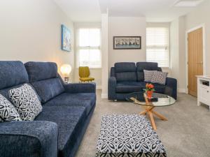 uma sala de estar com um sofá azul e uma mesa em Apartment 18 em Newton Abbot