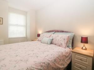 a bedroom with a bed with a pink bedspread at Apartment 18 in Newton Abbot