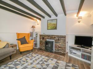 a living room with a fireplace and a tv at Honeysuckle Cottage in St Austell