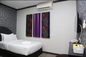a bedroom with a bed and two paintings on the wall at Vivids Hotel in Kuala Lumpur