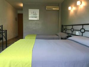 1 Schlafzimmer mit 2 Betten mit gelber und weißer Bettwäsche in der Unterkunft Hotel Arboledas Expo in Guadalajara