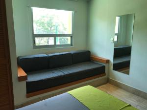 a couch in a room with a window and a mirror at Hotel Arboledas Expo in Guadalajara