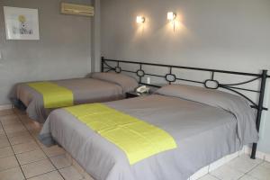 Hotel Arboledas Expo في غواذالاخارا: سريرين في غرفة ذات أغطية صفراء وبيضاء