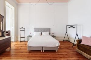 1 dormitorio con cama blanca y sofá en O da Joana, en Oporto