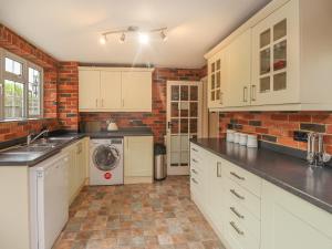 a kitchen with white cabinets and a brick wall at Knights Cottage in Maidstone