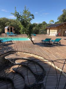 a group of benches sitting next to a swimming pool at Spa Les Jardins De Chiron Lodges et Tiny House dans le sud in Sauve