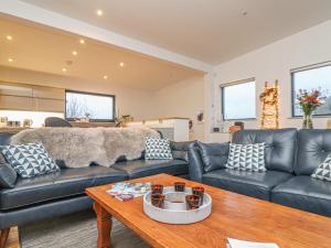 a living room with a black leather couch and a table at Idlewild, 2 Wheal Turnavore in St. Agnes 