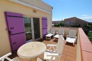 a balcony with chairs and a table and purple doors at Belle villa 5 couchages 2 chambres 2 terrasses piscine commune dans résidence securisée à 200m de la mer LRMA23 in Portiragnes