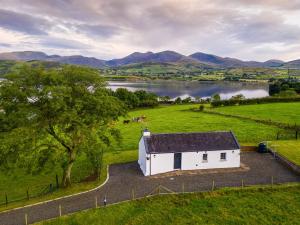 une vue aérienne sur un bâtiment blanc dans un champ avec un lac dans l'établissement Lough Island Reavy Cottage, à Newry