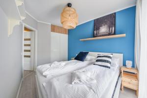 グダニスクにあるApartamenty Sun & Snow Cztery Oceanyの青いアクセントの壁のベッドルーム1室、ベッド1台が備わります。