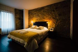 a bedroom with a large bed with a stone wall at Vougaldeias Casa da Tulha in Sever do Vouga