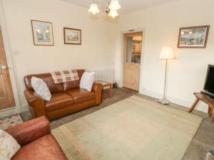 a living room with a couch and a television at Primrose Cottage in Hawes