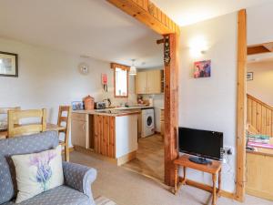 a living room with a tv and a kitchen at Stable Cottage in Keith