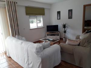 een woonkamer met twee witte banken en een televisie bij Quinta Das Amendoas in Carvoeiro