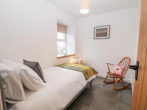 a bedroom with a white bed and a chair at Ysgubor Llwyd in Holyhead