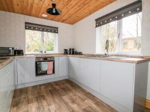 a kitchen with white cabinets and a wooden ceiling at Lodge Two in Truro