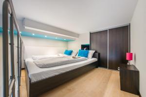 a bedroom with a large bed with blue pillows at Apartamenty Sun & Snow Nowa Slavia in Międzyzdroje