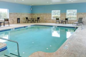 una piscina con sillas y mesas en un edificio en Holiday Inn Express & Suites West Long Branch - Eatontown, an IHG Hotel, en West Long Branch