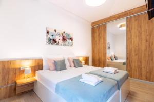 una camera da letto con un grande letto bianco con lenzuola blu di Apartments Fiorello a Fiume (Rijeka)