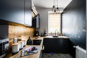 a kitchen with black cabinets and a sink at Blue House Warsaw Center in Warsaw