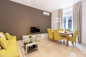 a living room with a dining room table and yellow chairs at Apartments Fiorello in Rijeka