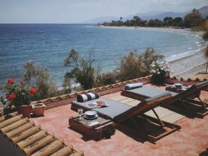 eine Terrasse mit einem Tisch, einem Grill und einem Strand in der Unterkunft The Artist's Farm in Dhiyeliótika