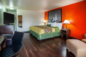 a hotel room with a bed with an orange wall at Super 8 by Wyndham Giddings in Giddings
