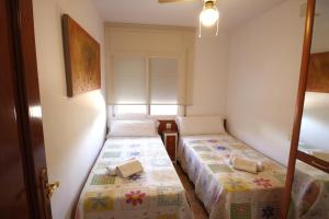 due letti in una piccola stanza con una finestra di Casa Carmen 1 a Miami Platja Altre 19 foto