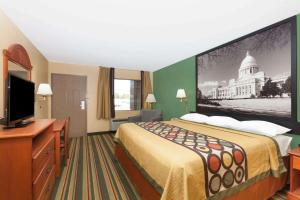 a hotel room with a bed and a flat screen tv at Super 8 by Wyndham Jacksonville AR in Jacksonville