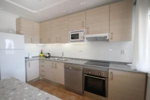 una cucina con mobili in legno e un frigorifero bianco di Casa Carmen 1 a Miami Platja