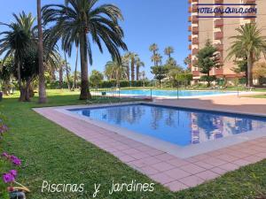 a swimming pool in a park with palm trees and a building at Las Gondolas 602 in Almuñécar