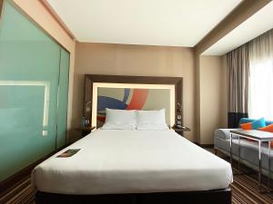 a hotel room with a large bed and a couch at Novotel Bangkok IMPACT in Nonthaburi