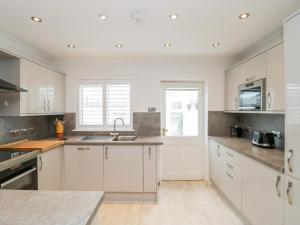 a kitchen with white cabinets and a sink at 14 Lyme Mews in Seaton