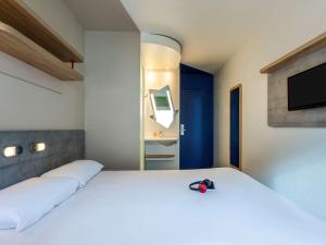 a bedroom with a large white bed and a television at ibis budget Paris Porte d'Italie Ouest in Le Kremlin-Bicêtre