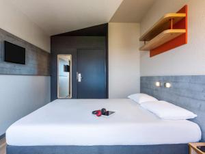 a large white bed with a pair of scissors on it at ibis budget Paris Porte d'Italie Ouest in Le Kremlin-Bicêtre