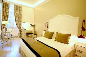 a bedroom with a large white bed and a desk at Hotel Royal Bon Repos in Sainte-Maxime